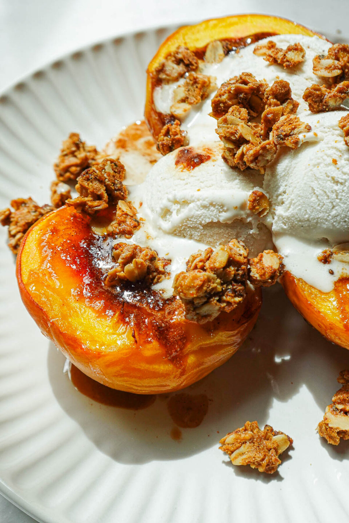 Close-up of caramelized air fryer peach halves with cinnamon sugar topping topped with dairy-free vanilla yogurt and crunchy granola