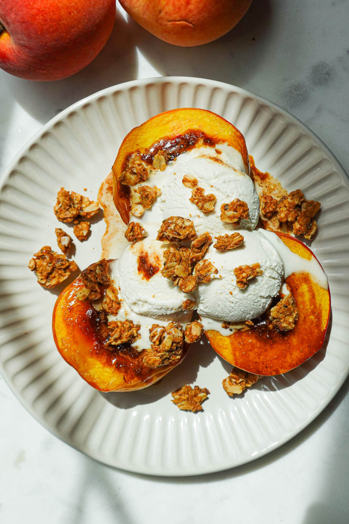 Air fryer peaches topped with vegan vanilla ice cream and granola