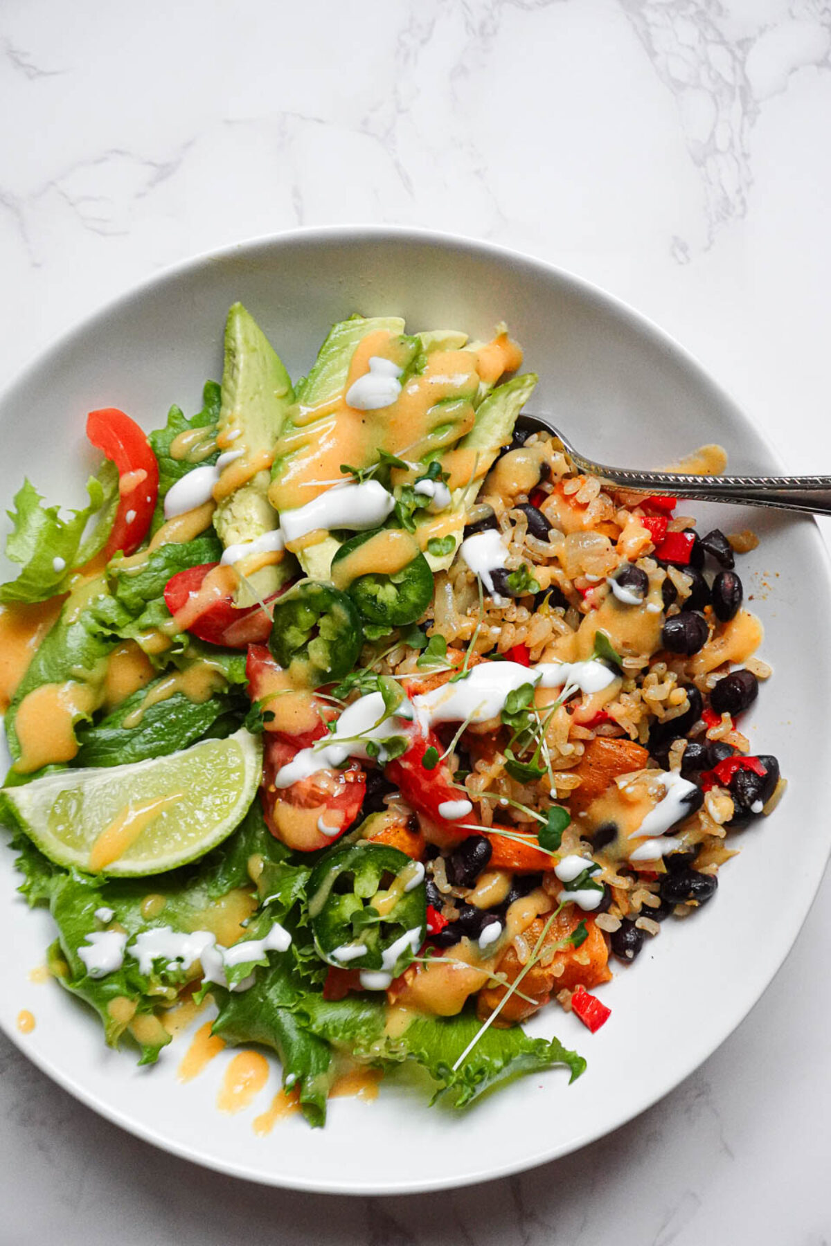 Plated vegan burrito bowl garnished with lime wedges