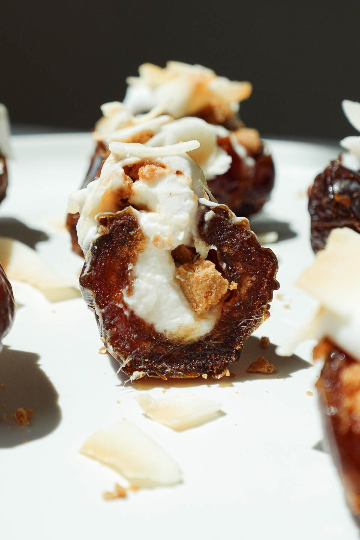 A bite taken out of a coconut cream pie stuffed date revealing the creamy coconut filling and chewy medjool date.