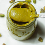 Creamy homemade pistachio butter in a glass jar with spoon