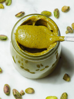 Creamy homemade pistachio butter in a glass jar with spoon