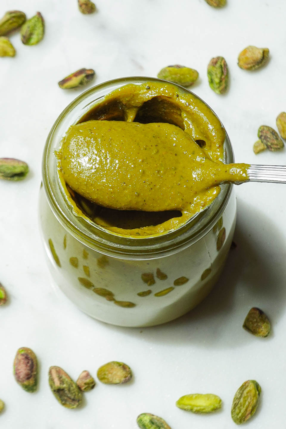 Creamy homemade pistachio butter in a glass jar with spoon