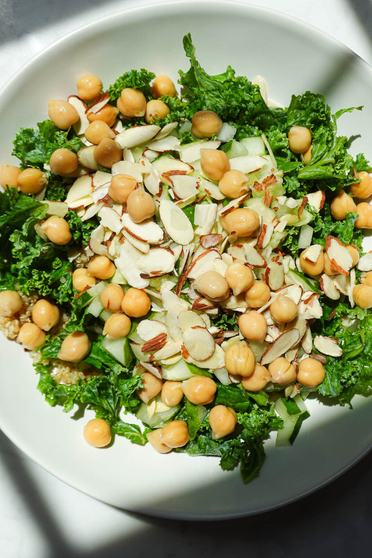 Close-up of quinoa salad with kale, chickpeas, cucumber, and sliced almonds