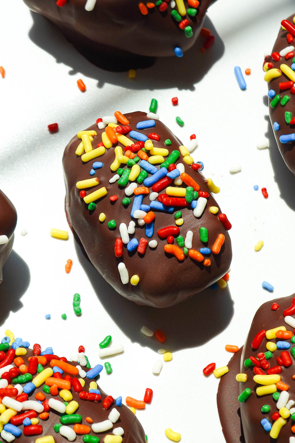 Cosmic brownie stuffed medjool dates with rainbow sprinkles on a white plate