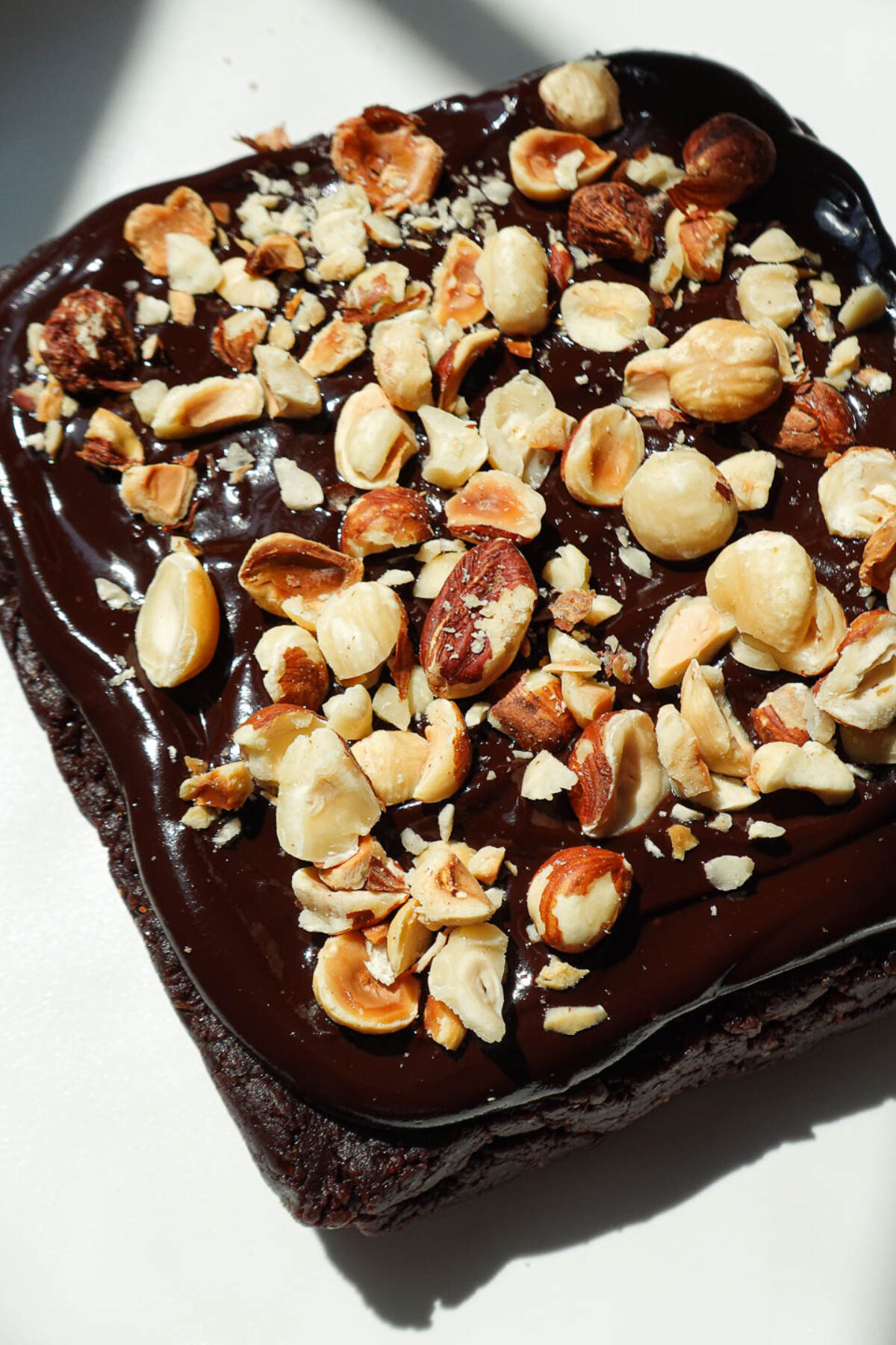Healthy vegan and gluten-free brownies made with dates and almond butter and topped with a 2 ingredient chocolate ganache and chopped hazelnuts