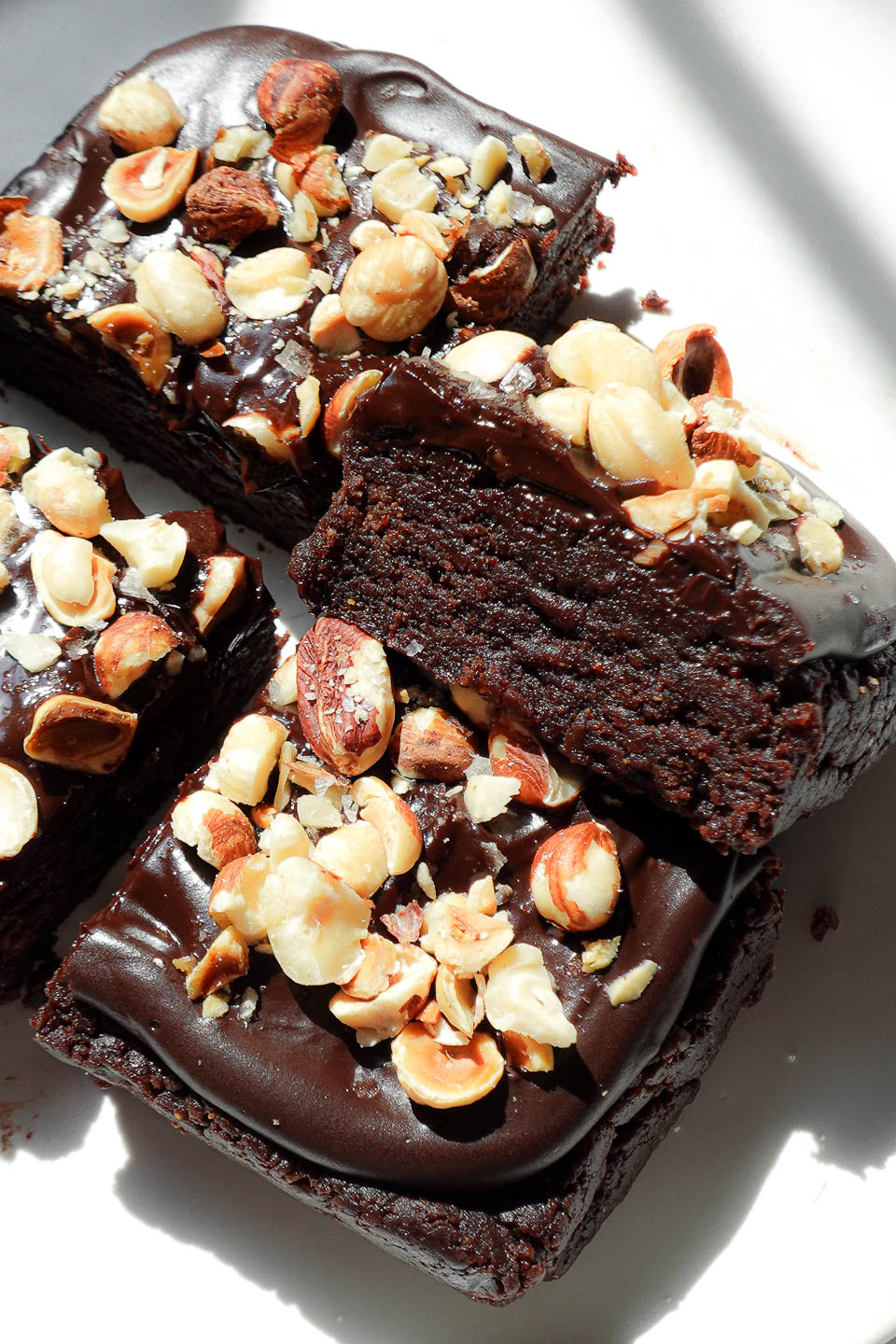Close-up of gooey no bake brownies topped with chocolate ganache and crunchy hazelnuts