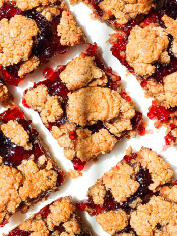 overhead shot of healthy peanut butter and jelly bars sliced on parchment paper with jam oozing out