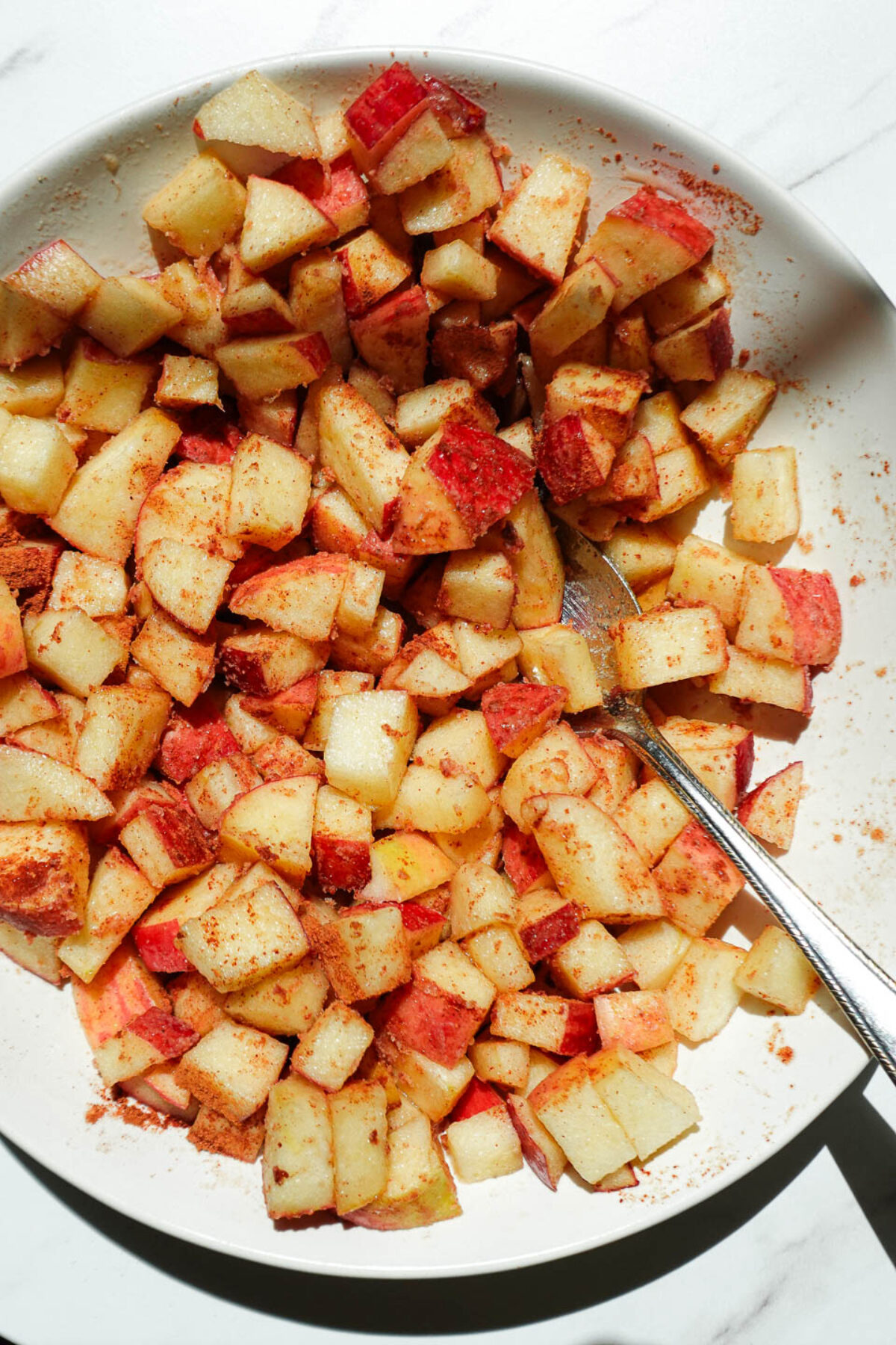 freshly diced apples in a bowl tossed with maple syrup and cinnamon