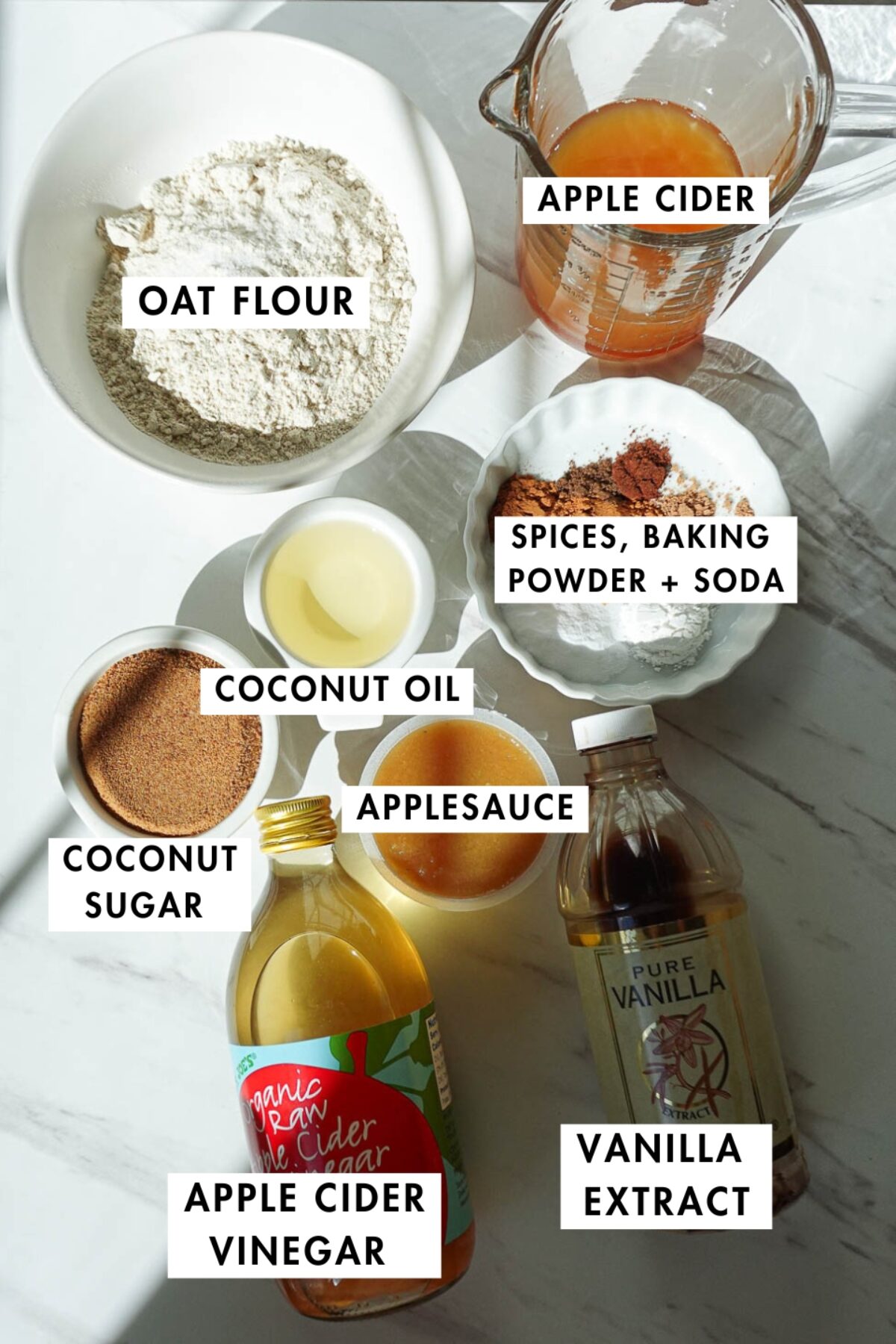 Ingredients for healthy apple cider muffins including oat flour, applesauce, apple cider, coconut sugar, and spices