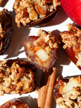 Bite taken out of an apple crisp stuffed date showing gooey date and cinnamon apple center