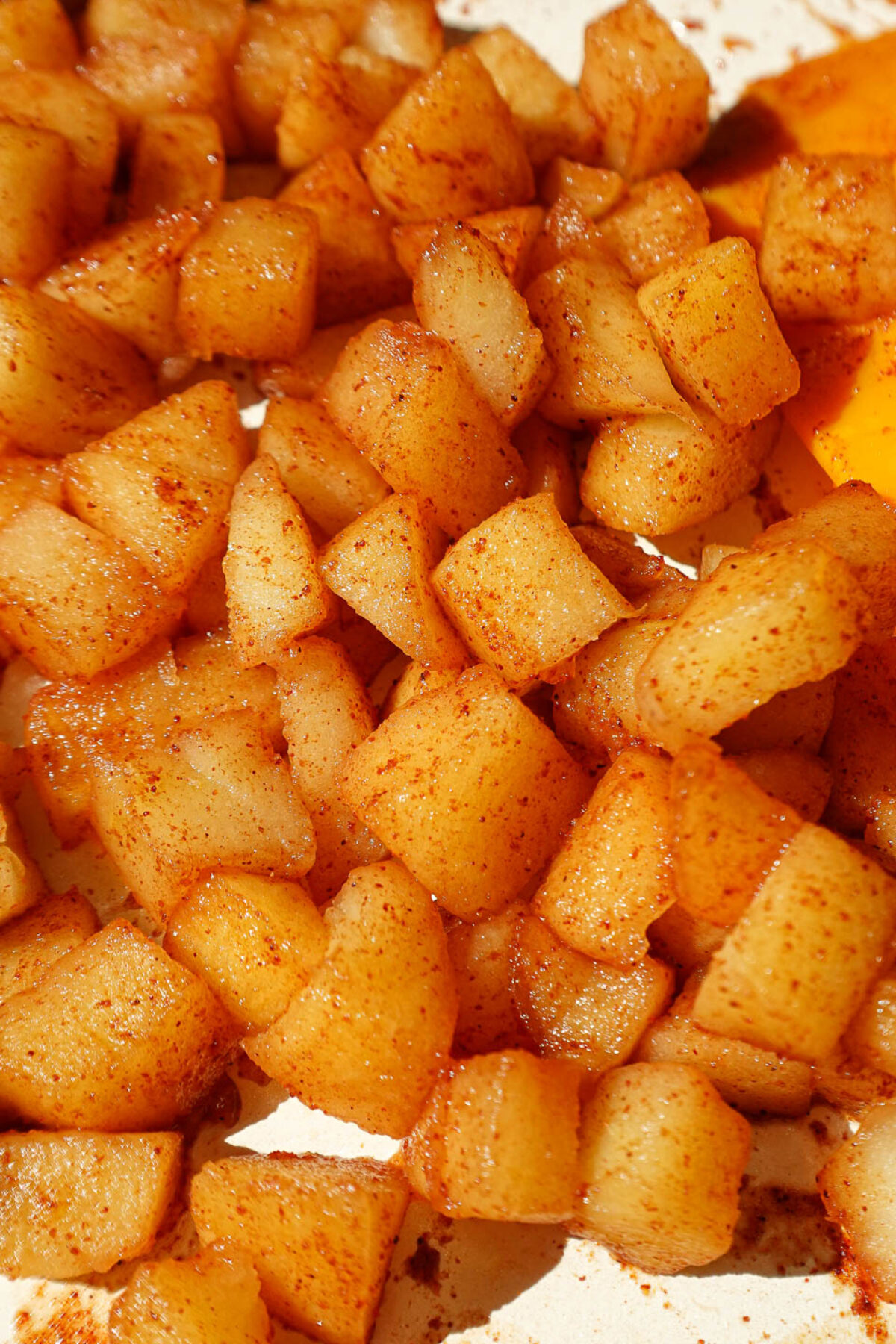 Diced apples sautéing with cinnamon and maple syrup in a skillet