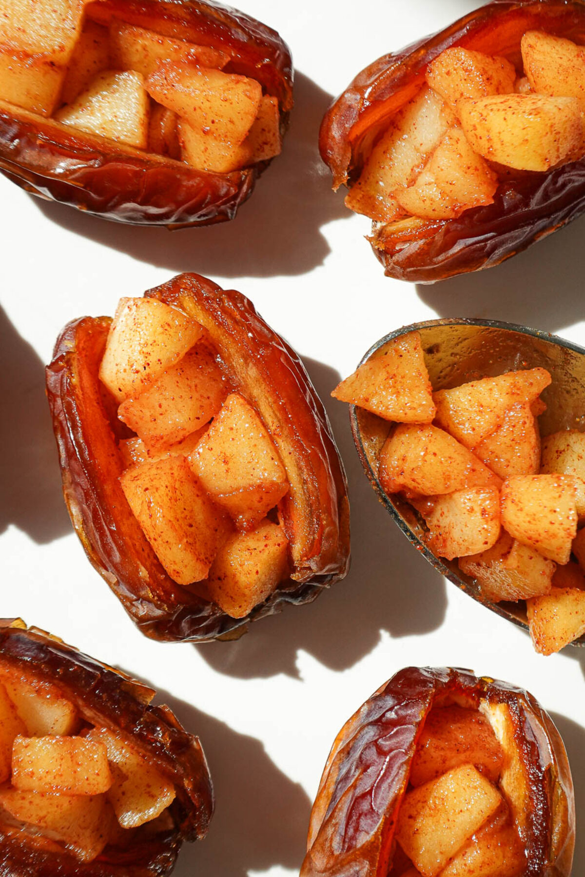 Medjool dates sliced open and stuffed with cinnamon apples on a baking sheet