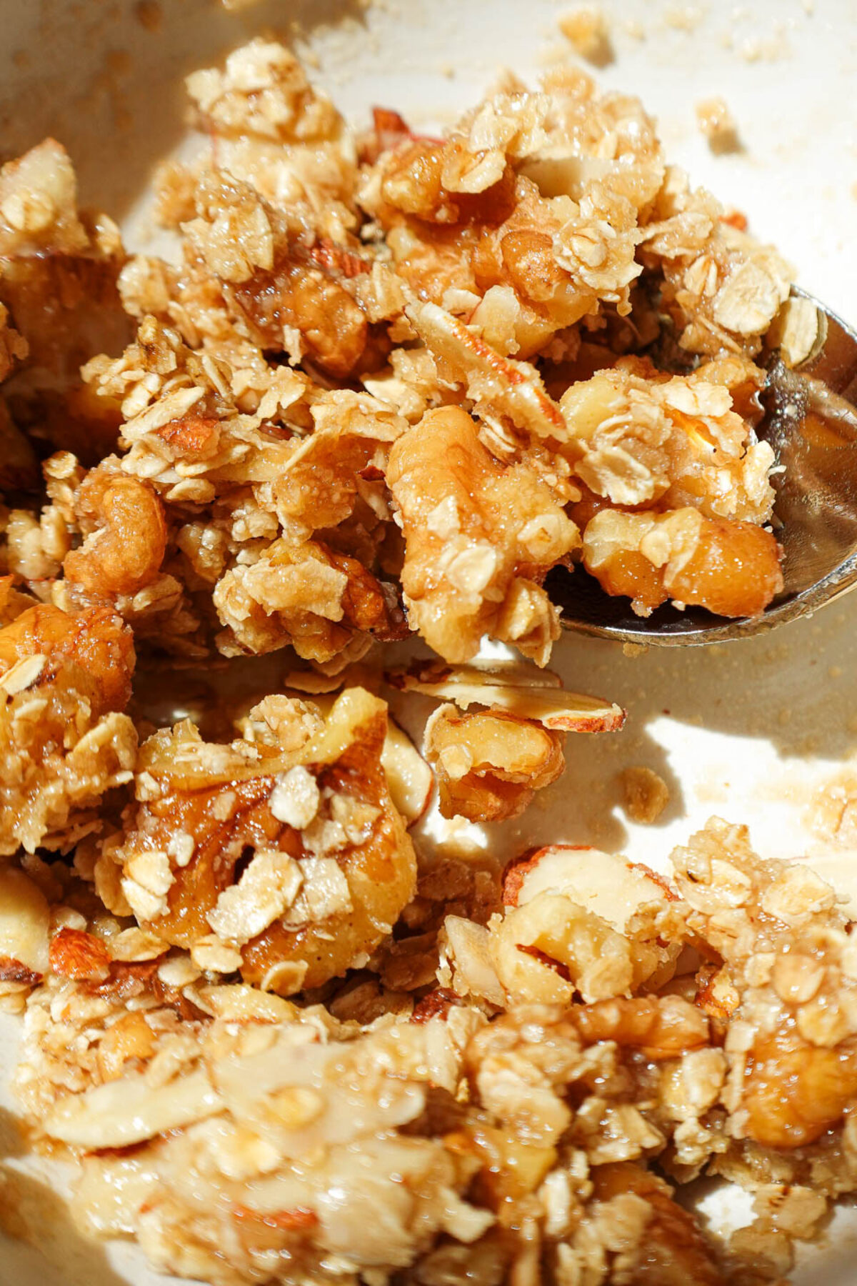 Mixing oat crisp topping with walnuts and maple syrup in a small bowl