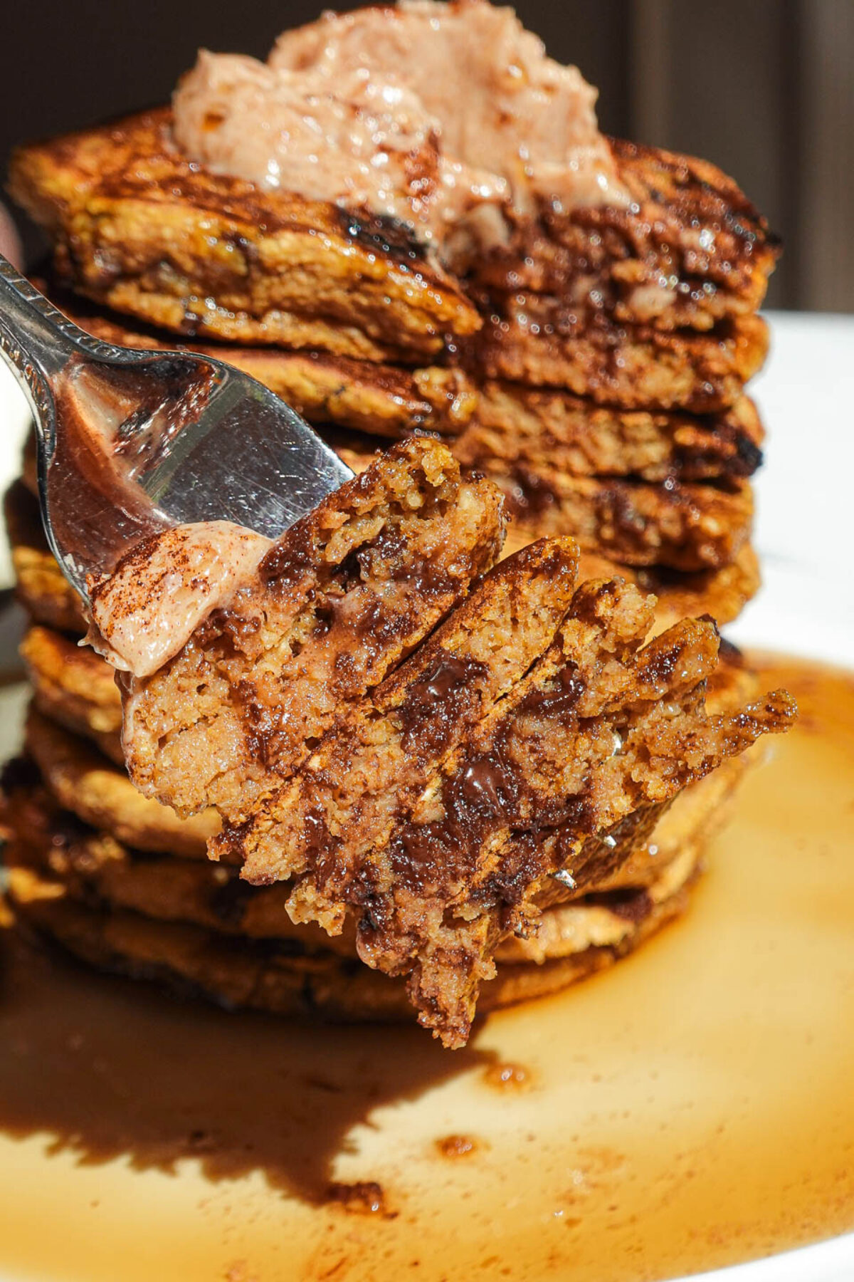 Close-up of vegan pumpkin chocolate chip pancakes with melty chocolate chips and maple butter
