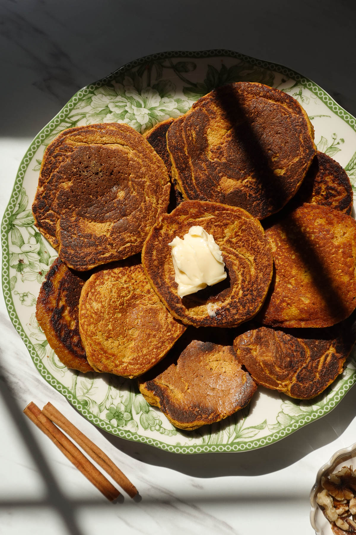 Vegan pumpkin pancakes topped with vegan butter on a plate.
