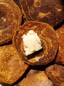 Close up of gluten-free pumpkin pancakes topped with vegan butter.