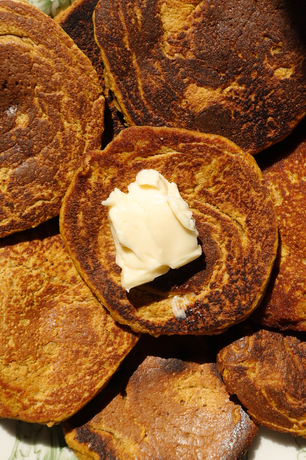 Close up of gluten-free pumpkin pancakes topped with vegan butter.