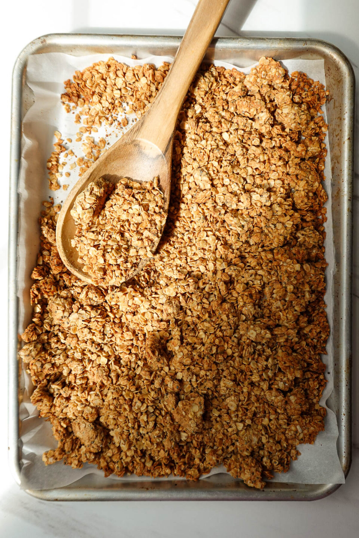 Homemade peanut butter granola cooling on parchment paper.