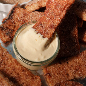 Close-up of a gingerbread French toast stick being dipped into creamy vanilla vegan yogurt