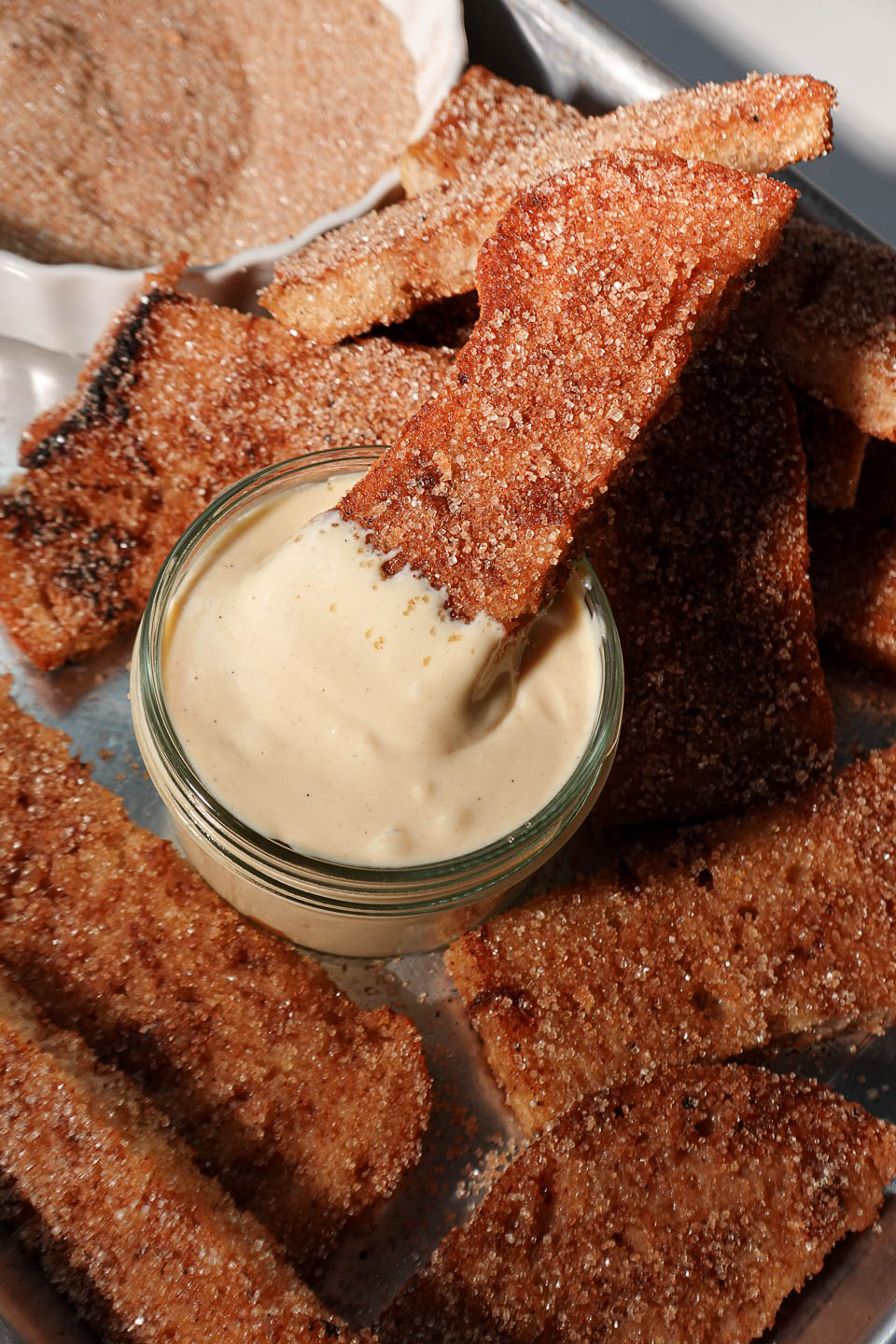 Close-up of a gingerbread French toast stick being dipped into creamy vanilla vegan yogurt