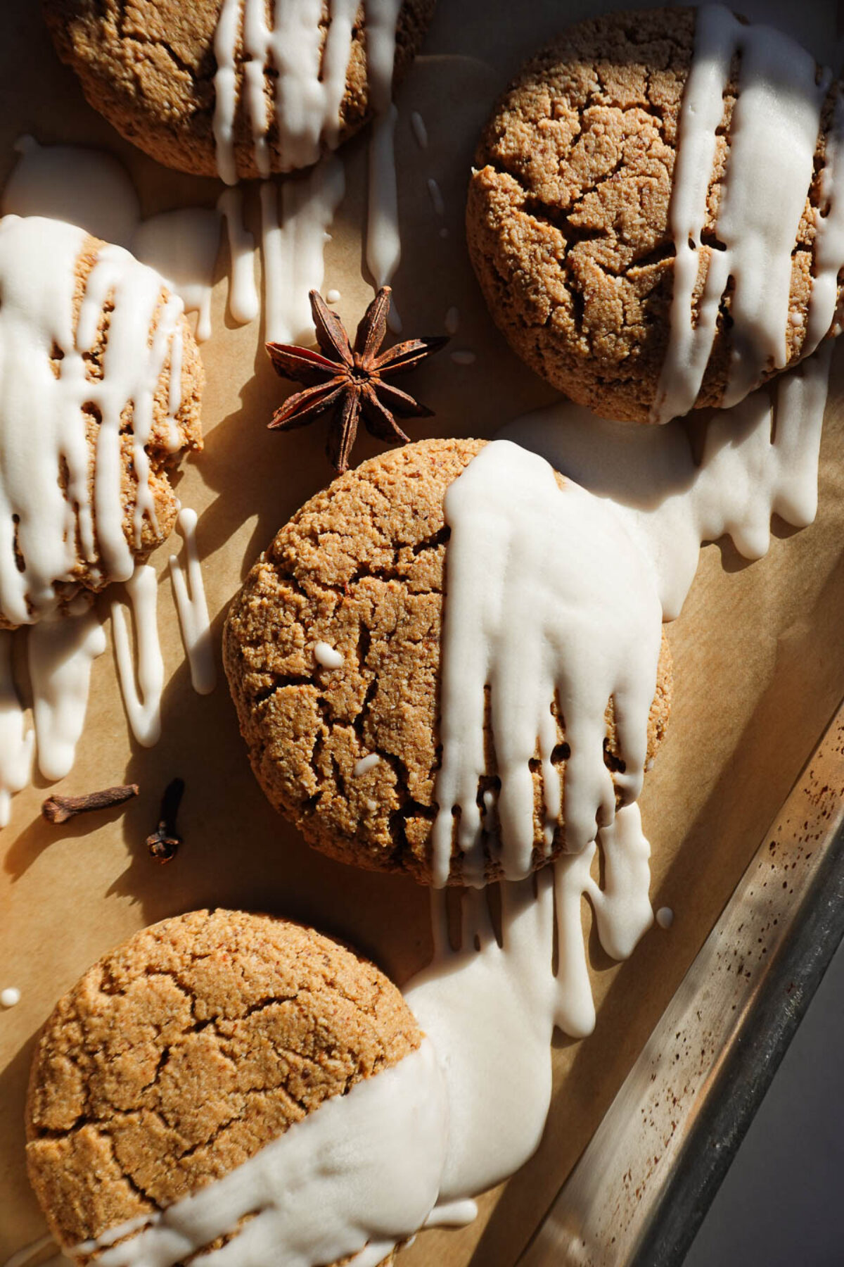 Soft and chewy gingerbread cookies drizzled with vegan white chocolate on a parchment-lined tray
