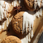 Soft and chewy gingerbread cookies drizzled with vegan white chocolate on a parchment-lined tray