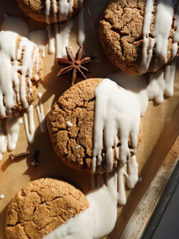 Soft and chewy gingerbread cookies drizzled with vegan white chocolate on a parchment-lined tray