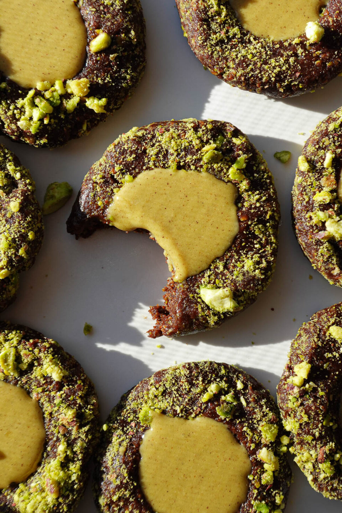 overhead shot of no-bake pistachio thumbprint cookies rolled in crushed pistachios and filled with pistachio butter