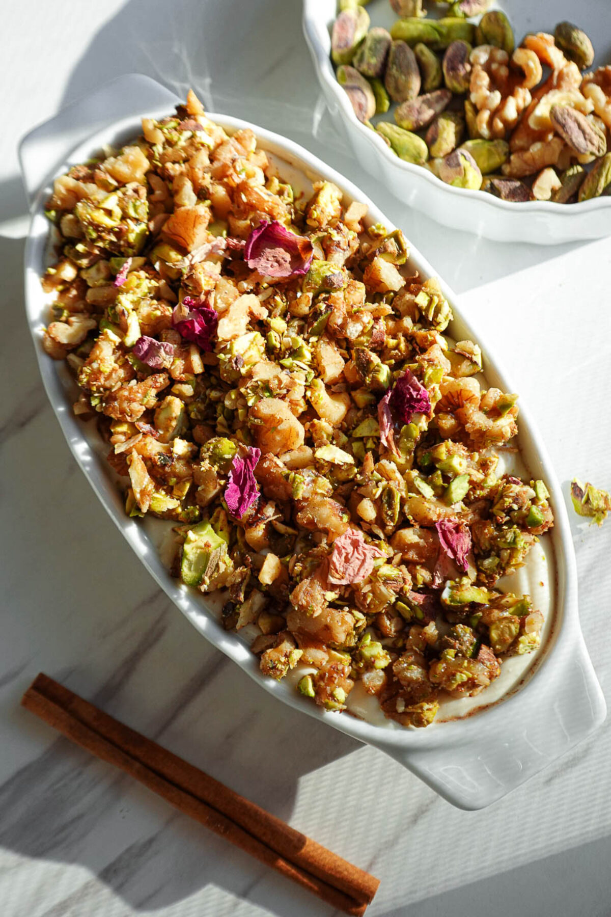 Baklava overnight oats topped with creamy vegan yogurt, pistachios, walnuts, and dried rose petals
