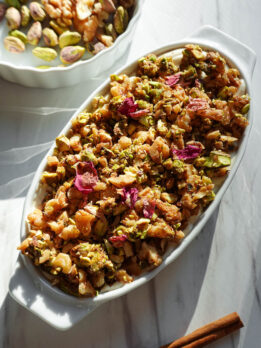 Baklava overnight oats topped with creamy vegan yogurt, pistachios, walnuts, and dried rose petals