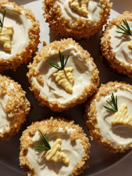Healthy carrot cake muffins topped with high-protein vegan cream cheese frosting