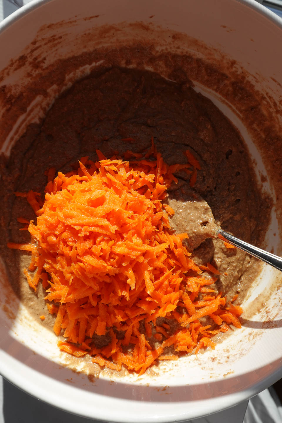 Mixing freshly grated carrots into one-bowl carrot cake muffin batter before baking