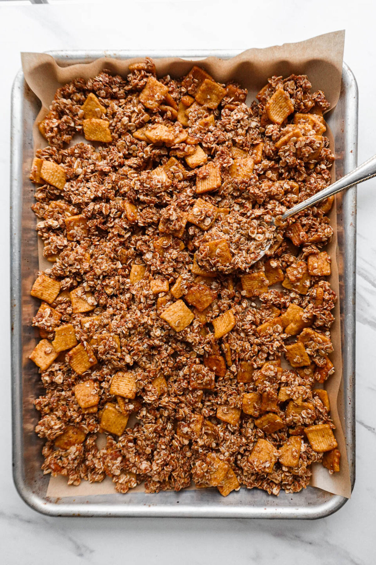 Healthy cinnamon toast crunch granola on a baking sheet before baking.