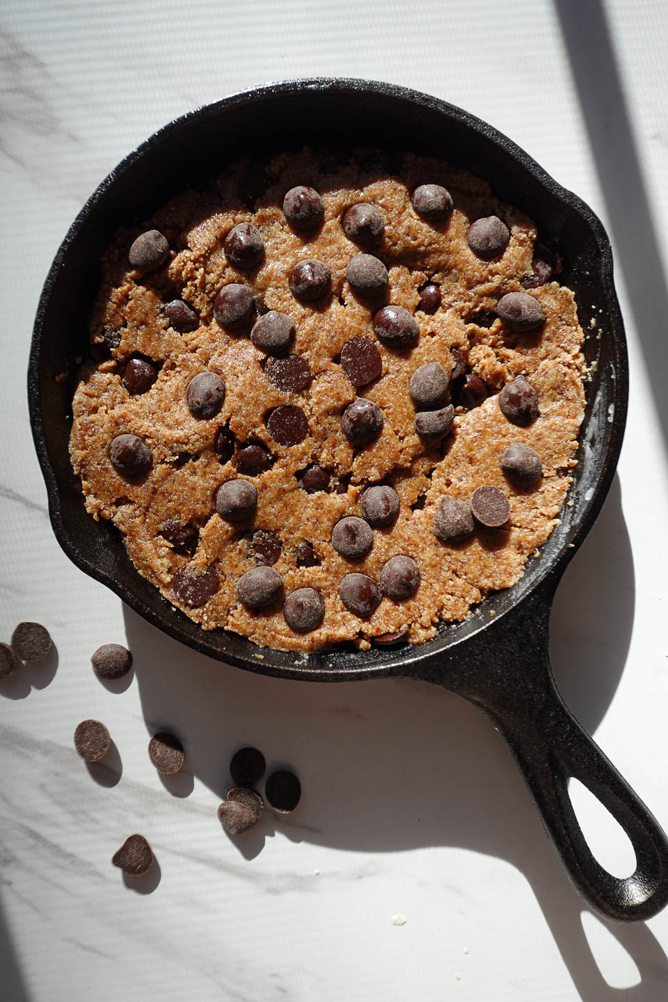 Sprinkling extra chocolate chips on top of skillet cookie dough before baking