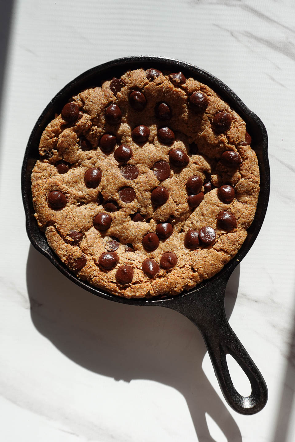 Baked chocolate chip cookie skillet with set edges and a soft, gooey center