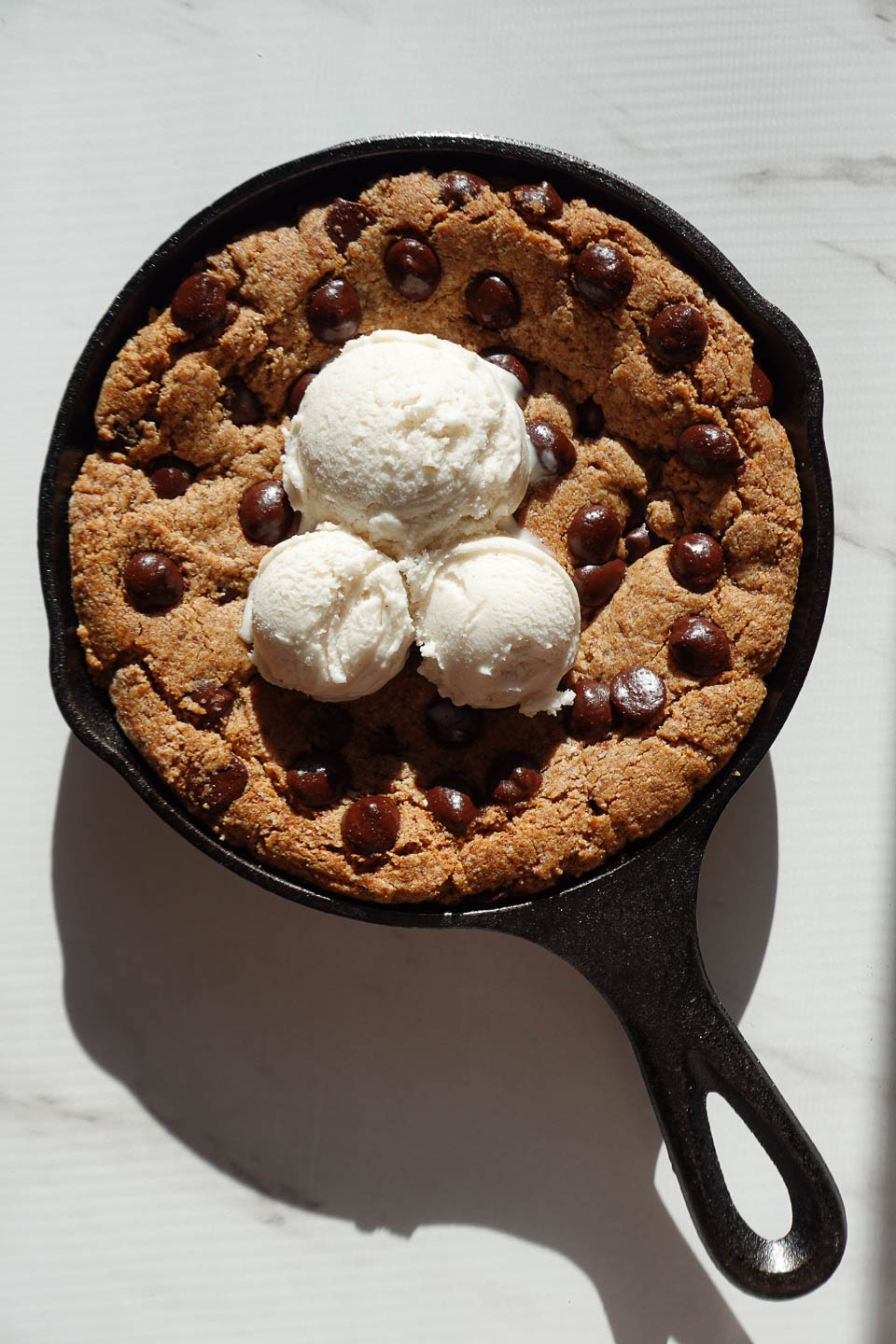 Adding scoops of ice cream to a warm chocolate chip skillet cookie