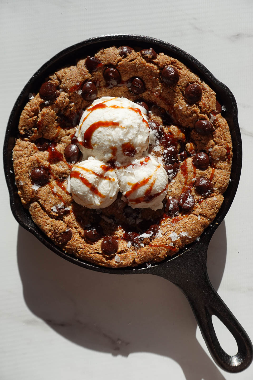 Drizzling date syrup and flaky sea salt over a chocolate chip cookie skillet à la mode