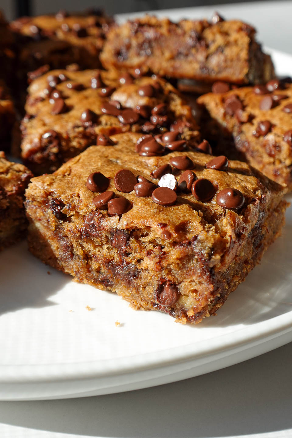 Close-up of a soft and moist vegan chocolate chip banana bar with melted chocolate chips throughout.