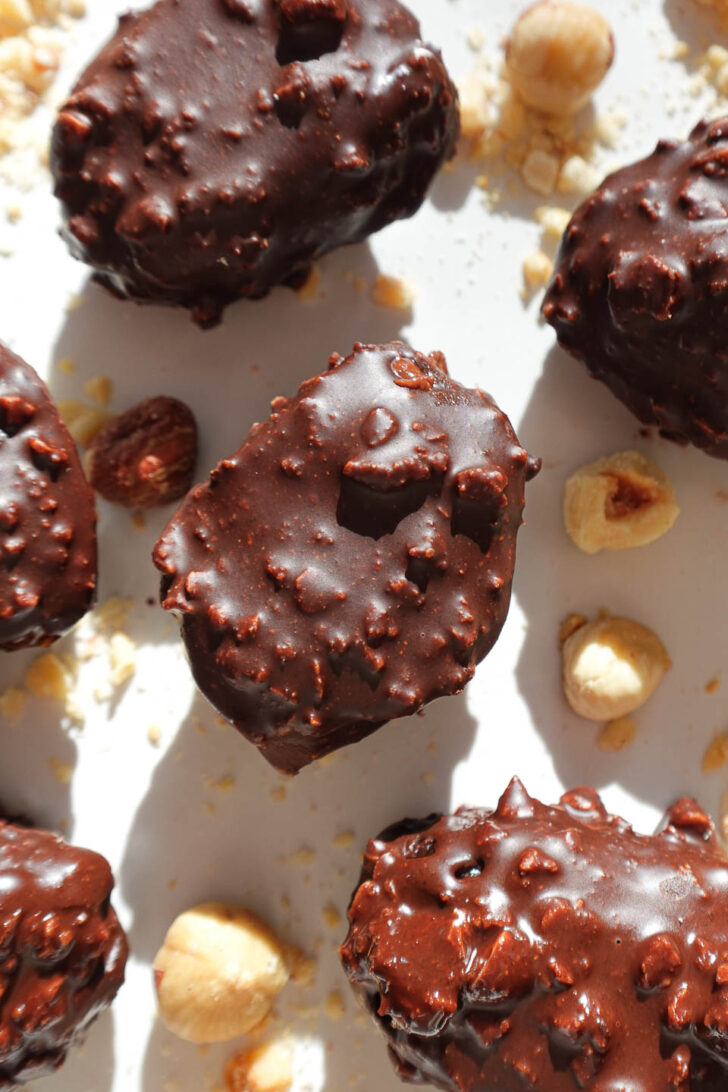 Close-up of Ferrero Rocher stuffed date with crunchy chocolate shell on a plate with hazelnuts