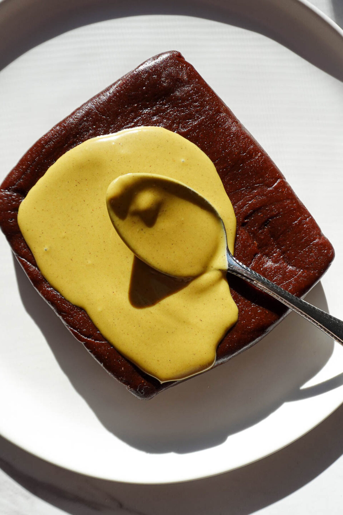 Spreading pistachio butter on top of no bake brownies