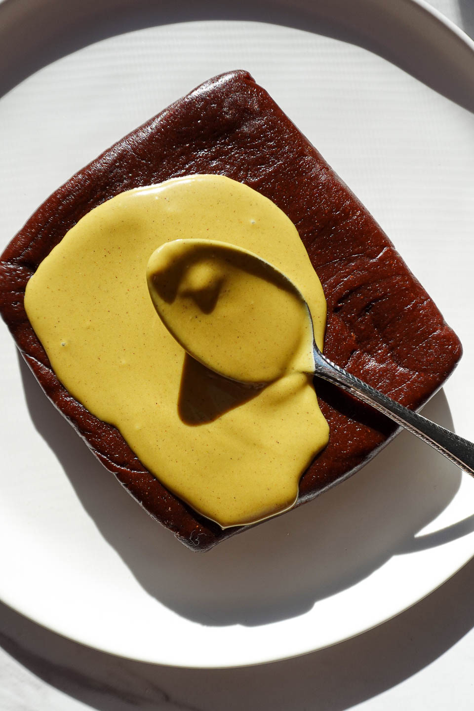 Spreading pistachio butter on top of no bake brownies