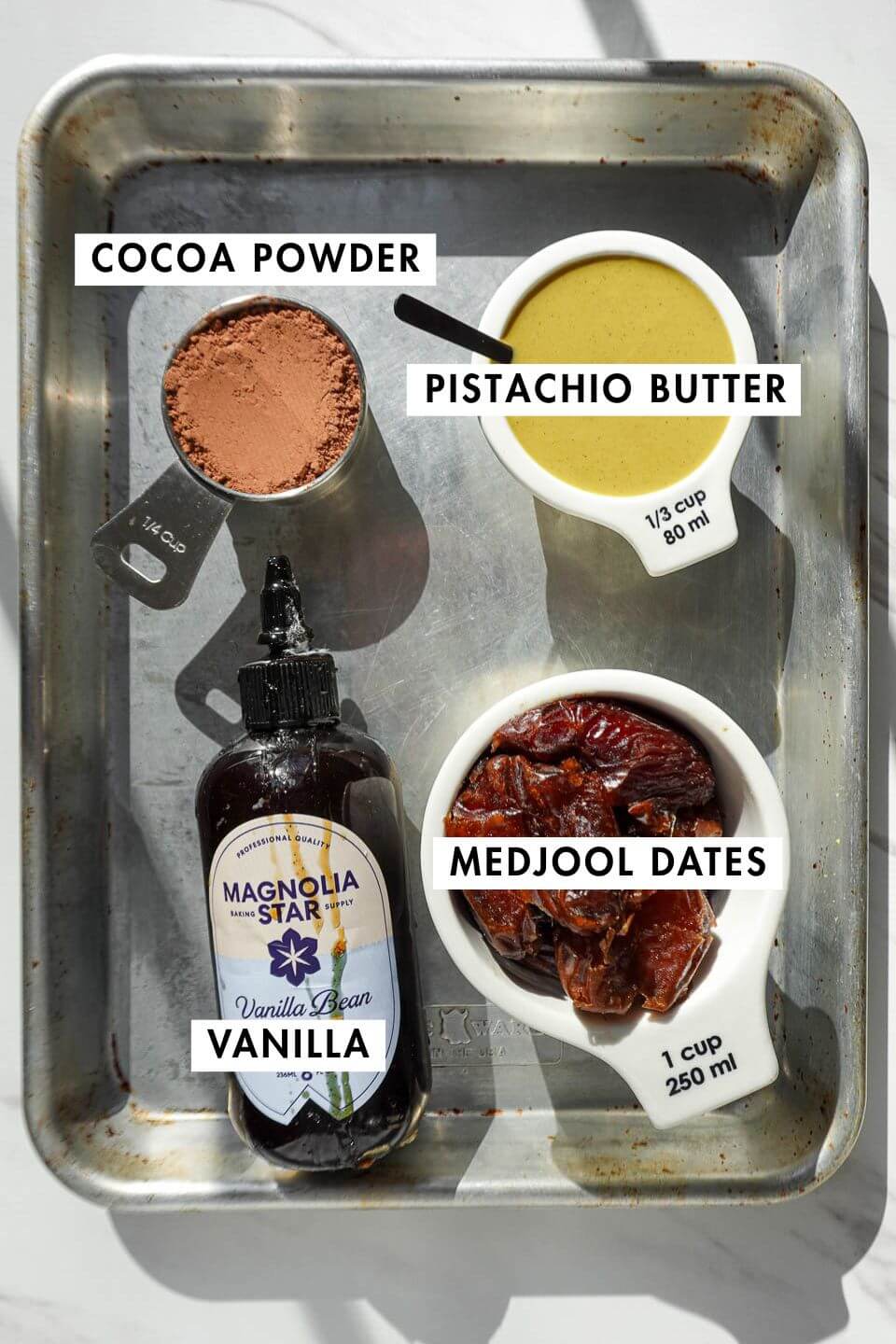 ingredients needed to make pistachio brownies including medjool dates, cocoa powder, pistachio butter, and vanilla extract