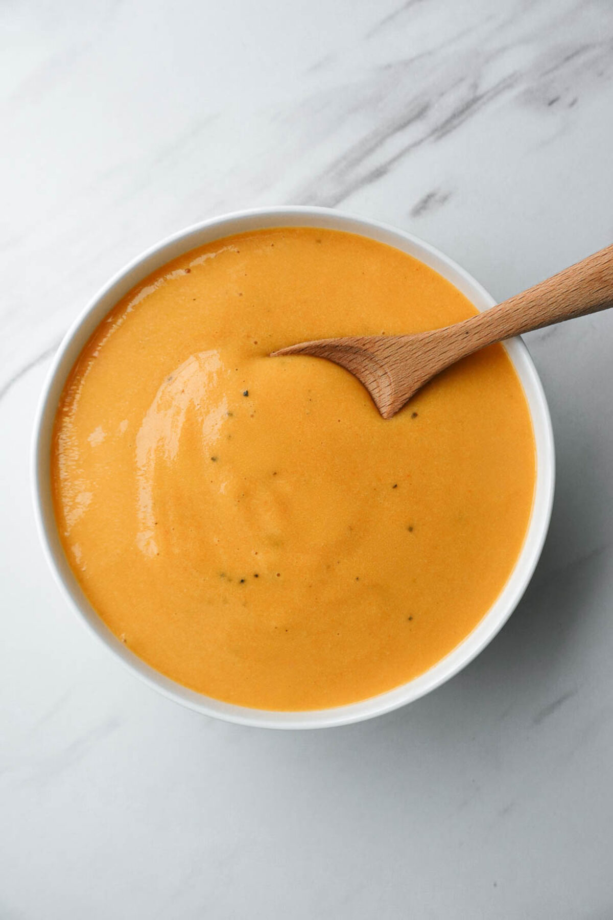 Creamy vegan cheese sauce made with potatoes and carrots in a white bowl