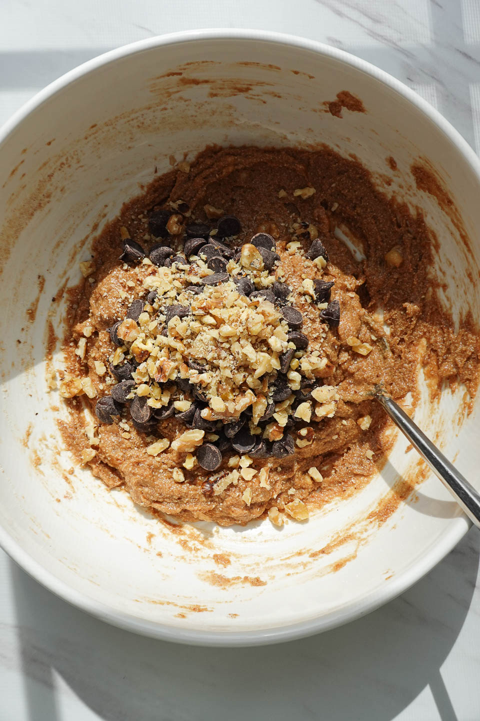 folding in chocolate chips and walnuts into banana bread cookie mixture
