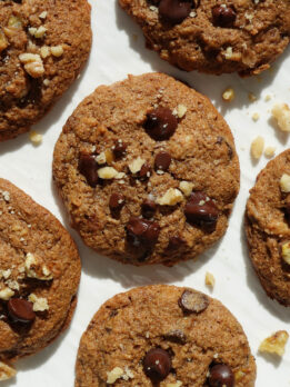 soft and chewy vegan banana bread cookies on a white plate sprinkled with crushed walnuts