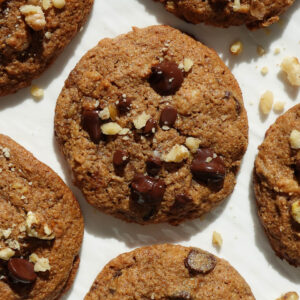soft and chewy vegan banana bread cookies on a white plate sprinkled with crushed walnuts
