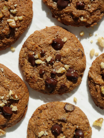 soft and chewy vegan banana bread cookies on a white plate sprinkled with crushed walnuts