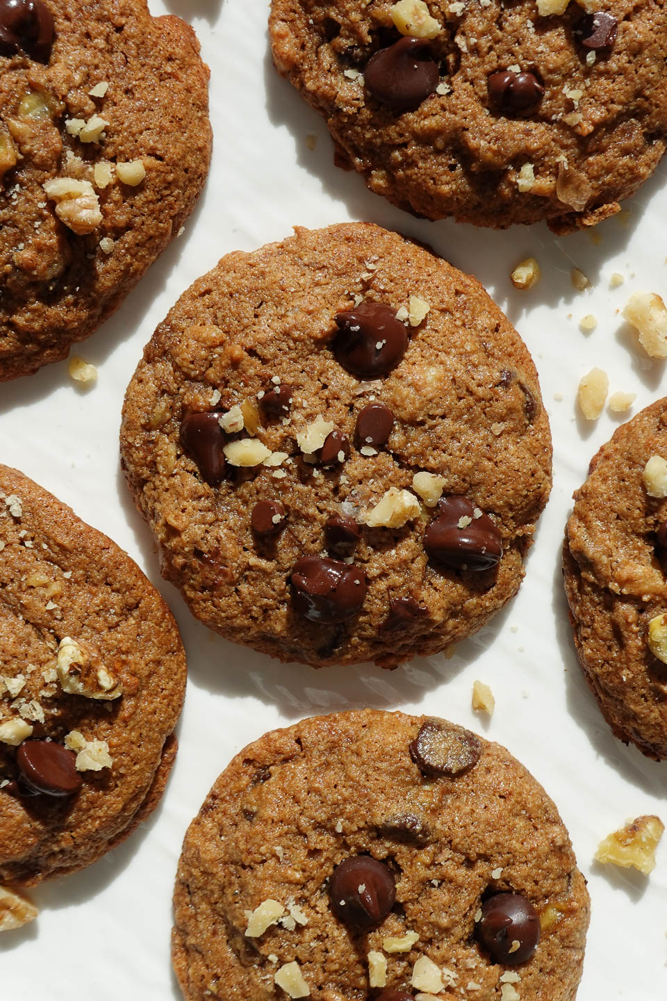 soft and chewy vegan banana bread cookies on a white plate sprinkled with crushed walnuts
