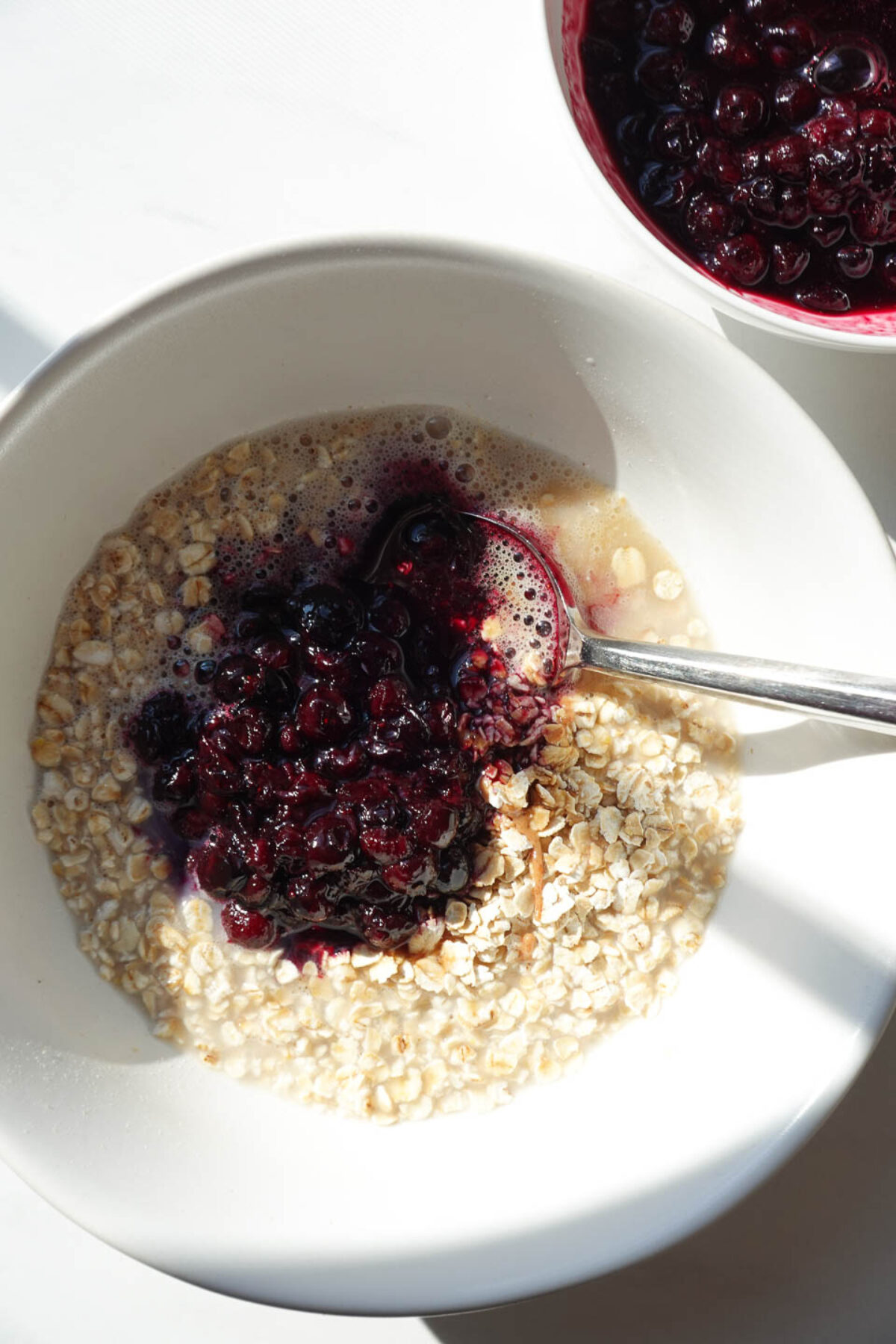 Stirring oats and blueberry compote together in a bowl